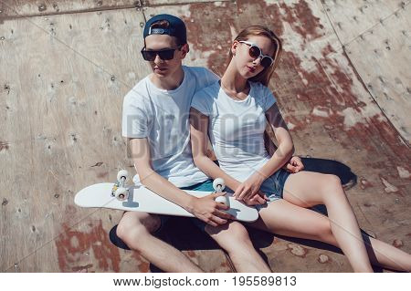 Young skater boy and girl skateboard posing in skate park.