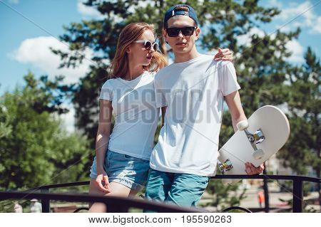 Young skater boy and girl with skateboard in white T-shirts on the street. Mock up.