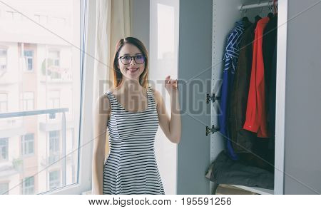 Young rednead girl choosing a clothes in wardrobe.