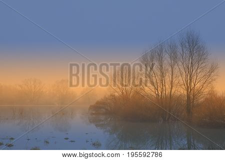 Magnificent colors from the rising sun in the fog over the spring flood.