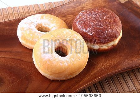 Assorted Homemade Doughnuts with Jelly filled and powdered sugar on wooden salver. Selective focus