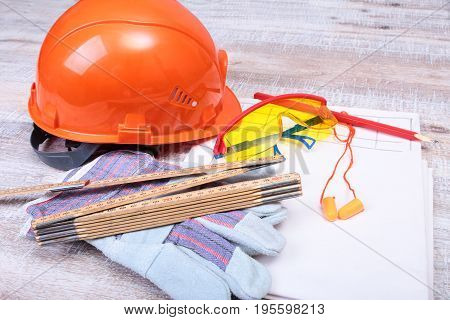 Orange hard hat, earplug, safety glasses and gloves for work. Earplug to reduce noise on a white background