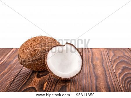 Tasty tropical coconut on a dack brown wooden table, isolated on a white background. Brown natural tropical and fresh fruit coconut. Close-up of tasty coconuts.