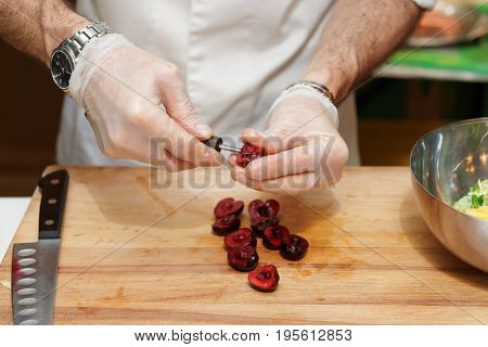 Chef is removing stones from cherry in professional kitchen