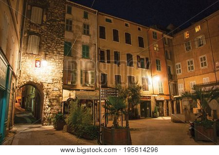 Draguignan, France - July 10, 2016. Night view of arch and square with buildings and light of lanterns, in the pleasant city of Draguignan. Provence region, Var department, southeastern France