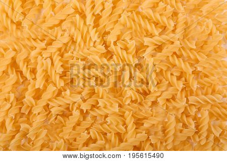 Close-up of the heap of uncooked pasta use as a background. Pasta is a staple food of traditional Italian cuisine. Yellow dry pasta textures background for Italian food ingredient.
