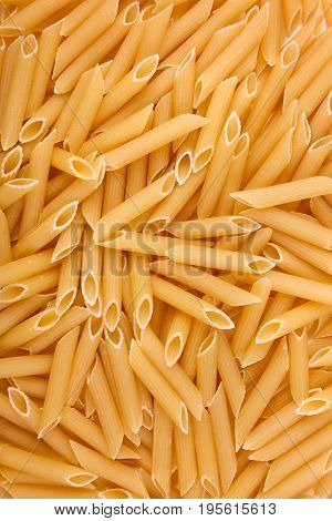 Italian penne rigate macaroni pasta and raw food on the background. Macaroni, noodle, and spaghetti in stock. Raw and fresh flour product. Macaroni texture. Full frame of dry pasta.
