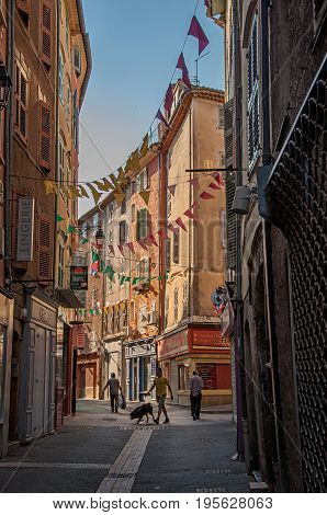 Draguignan, France - July 11, 2016. View of alley with townhouses and pedestrians in the city center of the lively and gracious town of Draguignan. Var department, Provence region, southeastern France