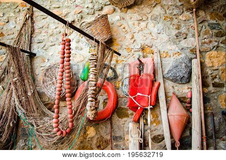 Old ancient fishing nets and tackes on the brick wall small fisherman village Avola Sicily Italy