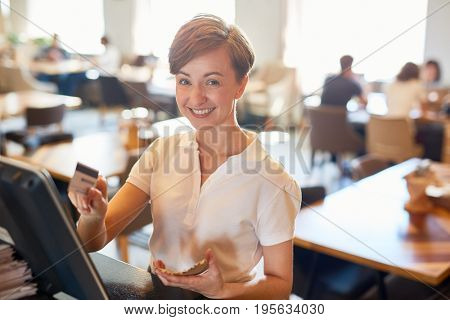 Successful staff of coffee-shop entering order of client in computer