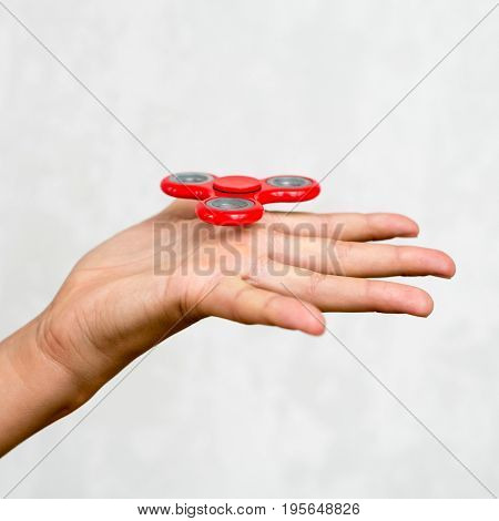 Red hand spinner. Boy playing a popular toy fidget spinner in his hand. Stress relief. Anti stress and relaxation adhd attention fad boy concept