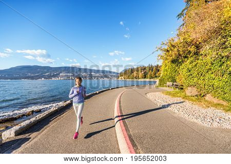 Runner girl running in Stanley Park Vancouver, British Columbia. Woman jogging in city outdoors enjoying healthy active lifestyle.