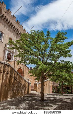 View of alley with trees and facade of the Grimaldi Castle in Haut-de-Cagnes, a pleasant village on top of a hill, near Nice. In the Alpes-Maritimes department, Provence region, southeastern France
