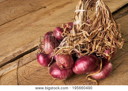 Fresh red onions on old rustic wodden table. Raw rustic vegetables on wooden board