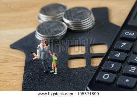 Miniature happy family figure standing on paper house with calculator as mortgage or financial investment plan concept.