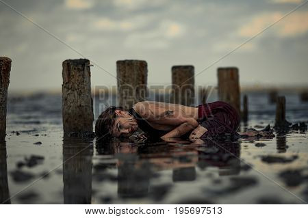 Young woman bathing in therapeutic water of mud estuary, next there are her reflection and wooden columns. Spa.