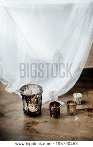 Glass With Candles On The Wood Floor And White Fabric On Background