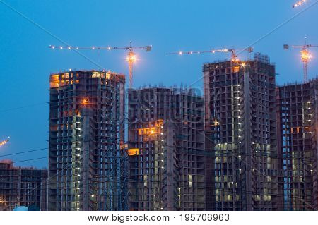 Under construction building with lights and cranes shot during evening. Many such real estate projects have come up in delhi and Noida to house the ever growing population