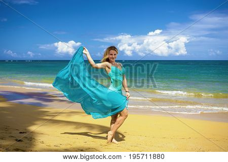 Young beautiful girl with blue pareo on tropical beach