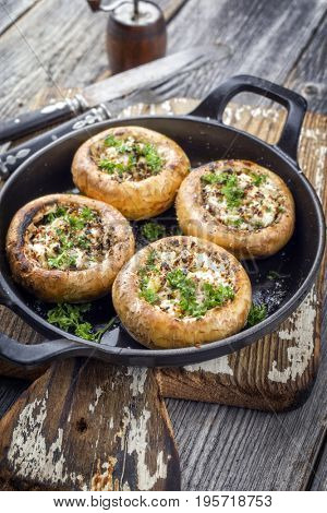 Traditional Italian Mushroom Caps stuffed with Feta as close-up in a rustic frying pan 