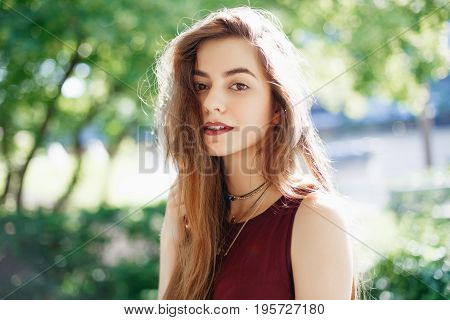 Portrait of smiling innocent Caucasian middle eastern blonde young beautiful woman with long hair and brown eyes looking in camera. Girl with with natural beauty emotions outside on summer day.