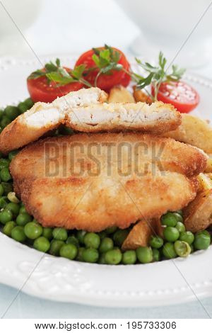 Breaded chicken breast steak with roasted potato and green peas