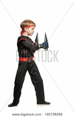 Young male fighter exercising with kunai throwing knives. Cosplay hero ninja