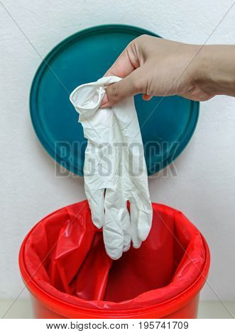 Closeup cropped portrait healthcare professional throwing away blue disposable latex gloves in trash.lsolated lab background.infectious wastes in red bag in hospital.
