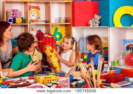 Small students painting in art school class. Child drawing by paints on table. Girl make candy cone schultuete in kindergarten for school.