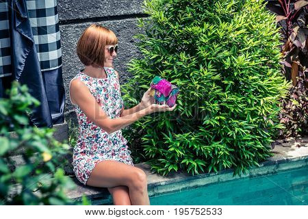 Summer portrait of a beautiful sexy girl with sunglasses and luxury handmade snakeskin python handbag in the swimming pool. Fashion outdoor. Tropical Bali island.