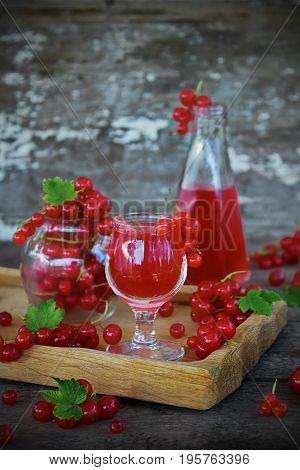 ликер из красной смородины в рюмке и свежие ягоды на старом фоне