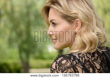 Beautiful middle aged woman having a rest at a park on a summer day. Mood of summer and carefree vacations. Beauty, cosmetics.