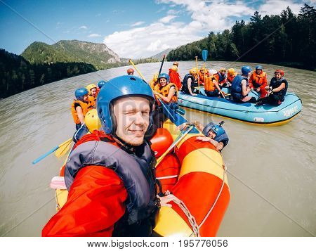 mountain Altai, biryuzovaya katun, RUSSIA - July 16, 2017: man in a helmet holds an action camera and makes selfie on the background of friends with oars, rafting