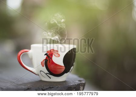 White cup morning coffee in garden and sunrise