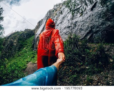 girl in a raincoat in the rain leads the guy to the mountain. Concept follow me to the mountains.
