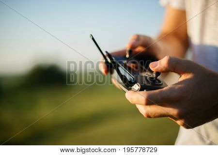Man holds a drone remote controller in his hands. Close-up of quadcopter RC with antennas during flight. Pilot takes aerial photos and videos with quad. No face