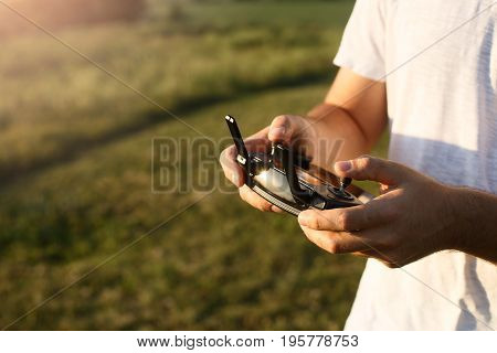 Man holds a drone remote controller in his hands. Close-up of quadcopter RC with antennas during flight. Pilot takes aerial photos and videos with quad. No face