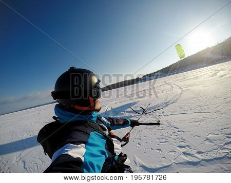 man athlete on alpine skiing with snowkite against a blue sky.