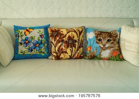 Close up three hand-made decorative cushions with embroidery on modern sofa