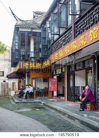 Suzhou, China - Nov 5, 2016: Restaurant and tea house in the historic Zhouzhuang Water Town. Some folks sitting outside the stores.
