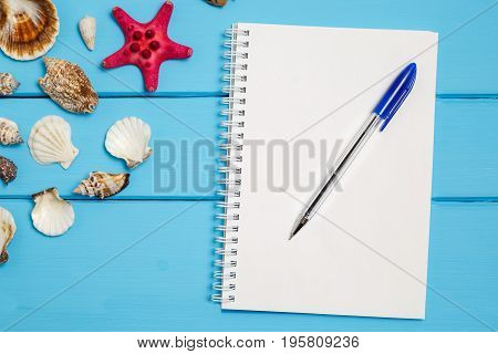 Blank notepad and different marine items on blue painted wooden background. Sea objects on wooden planks. Selective focus. Place for text.