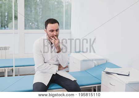 Thoughtful doctor sitting in a operating room with his hand on head.