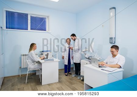 Group Of Doctors Involved In Serious Discussion With Medical Records.