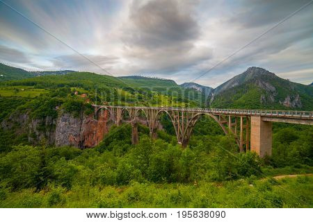 Durdevica arched Tara Bridge over green Tara Canyon at evening time - Montenegro