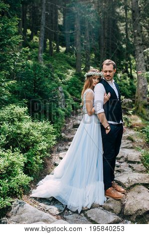 beautiful bride in a blue dress and a wreath of white flowers with the bride are in the wood.
