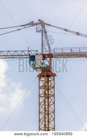 Construction tower crane cabin in the blue sky and clouds vertical