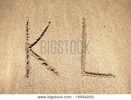 ตัวอักษรตัวอักษร L K มือในทรายบนชายหาดสวยงาม