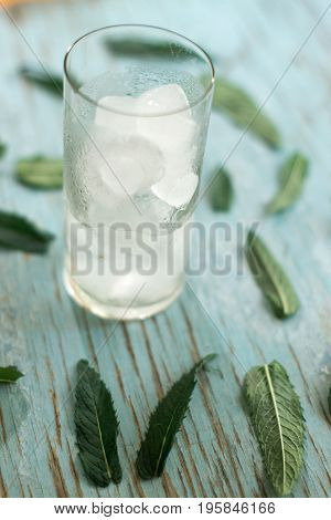 Glass with ice and mint leaves on a blue background