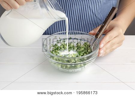 Step By Step Recipe For Tarator. Hands Pour Yogurt Into A Bowl With Mixed Vegetables.