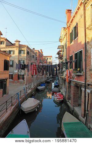 Specific canal with parked boatsspecific architecture and clothes hanging out to dry in VeniceItaly.